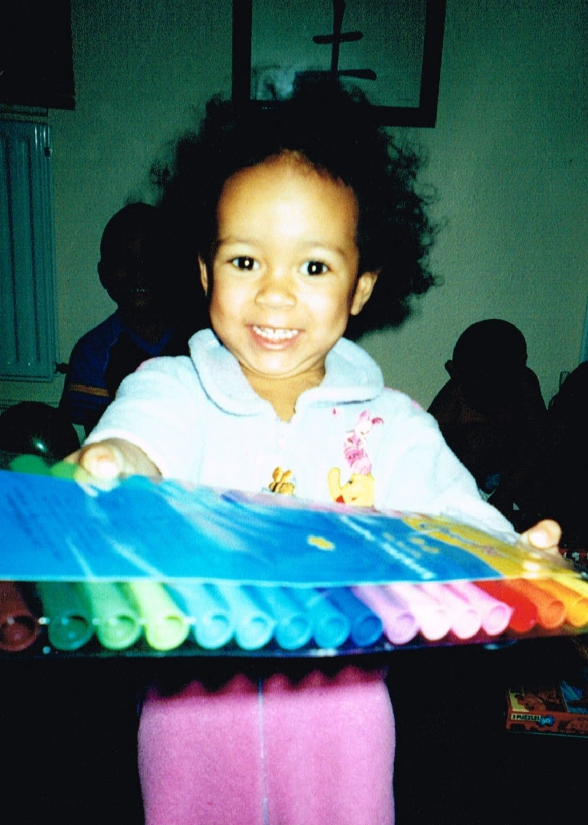 Artist Naomi Richards as a young child, smiling as she receives a gift of felt tip pens